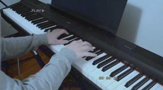 Screenshot from one of Madalyn's Five Nights at Freddie's videos. It's her hands playing keyboard done in a choppy VHS, home recording style. A "Play" button is at the top left.